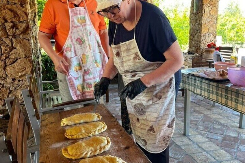 Two people cooking on an outdoor grill with aprons. 5
