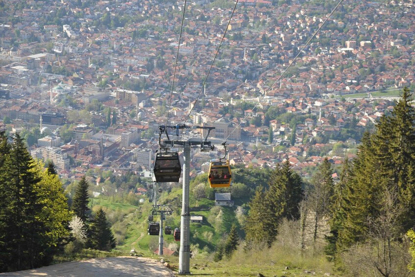 A cable car system with cabins descending a mountain towards a densely populated town. 3