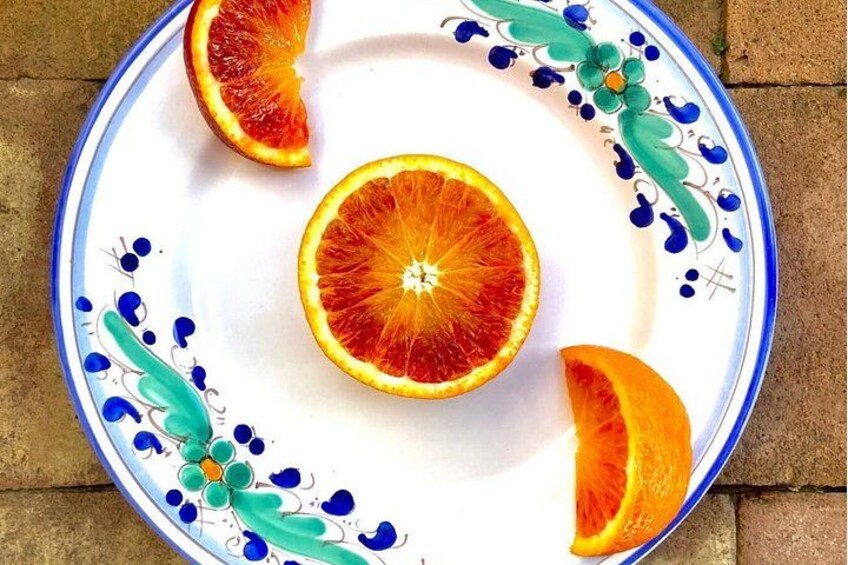 A plate with a decorative design and three halves of a blood orange. 3