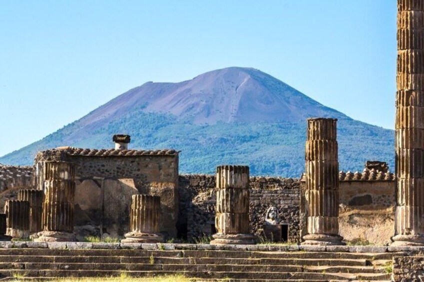 Ancient ruins with columns and a mountain in the background. 2