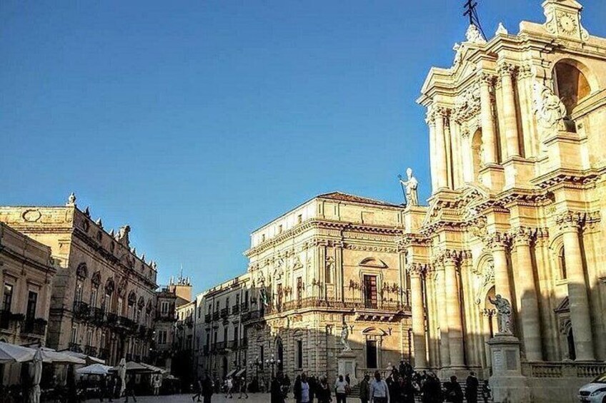 A historic square with ornate buildings, a prominent church, and a clear blue sky. 3