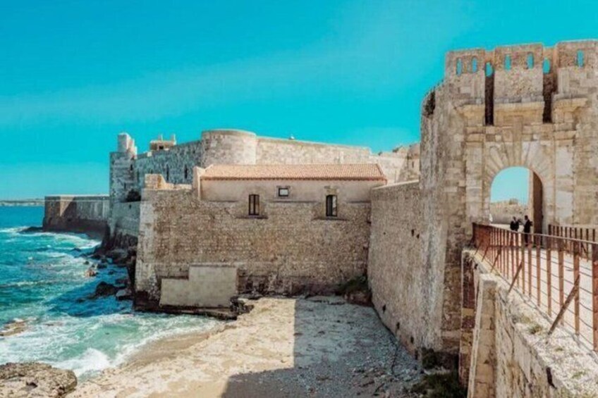 A coastal fortification with a stone wall, a sea wall, and a clear blue sky. 2