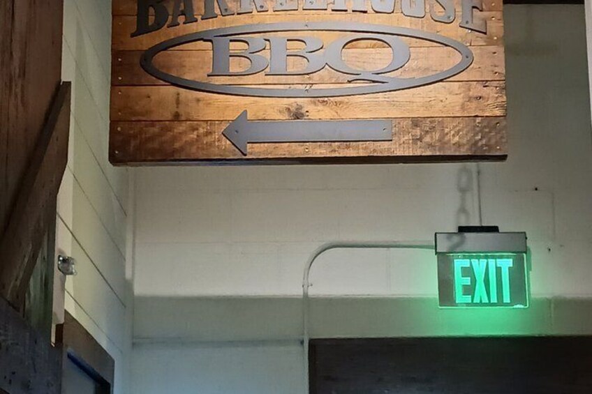 A wooden sign for 'Barbecue BBQ' with an arrow pointing left and an exit sign above it. 3