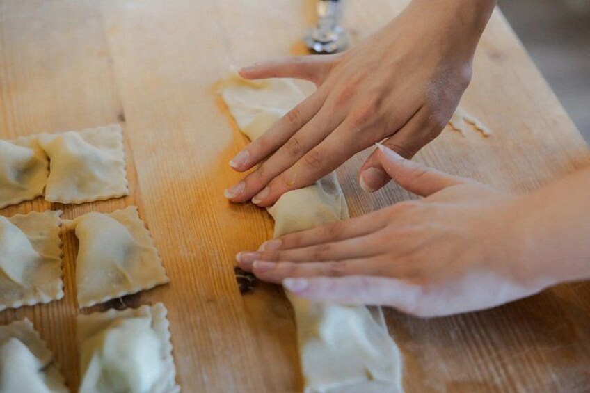 Hands shaping dough on a wooden surface. 4