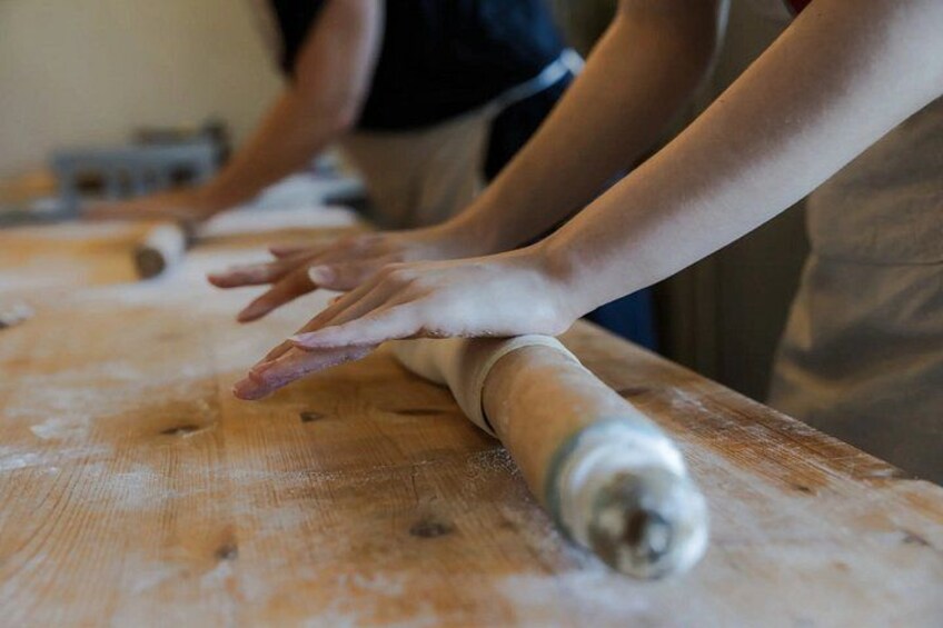 Hands rolling dough on a wooden surface. 5