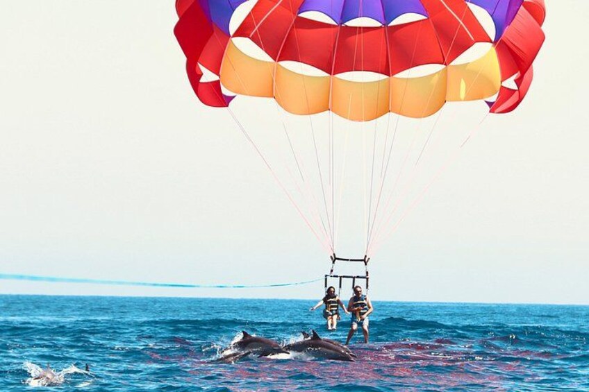 A person parasailing over the ocean with a colorful parachute. 2