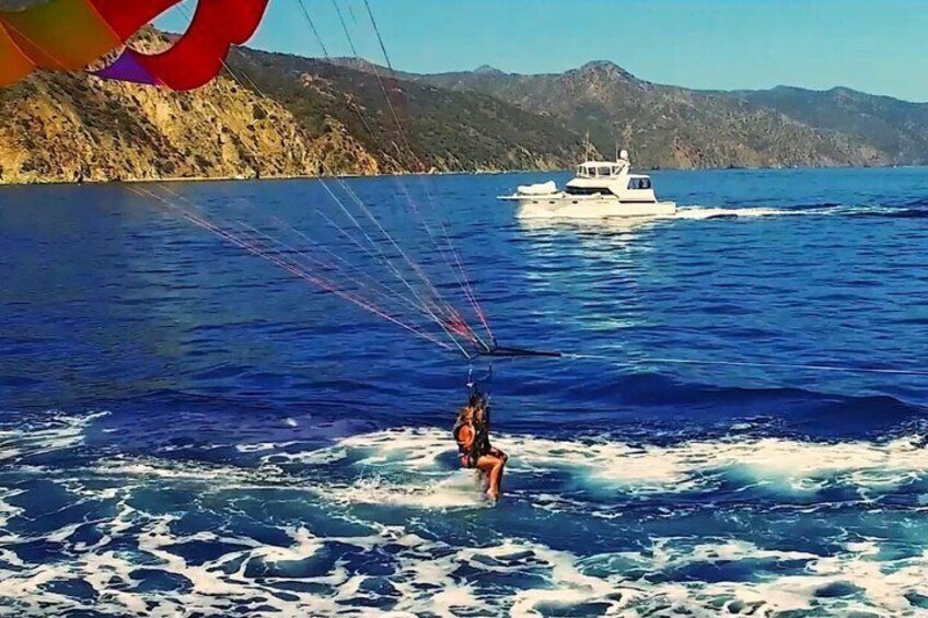 A person parasailing over water with a boat in the background. 5