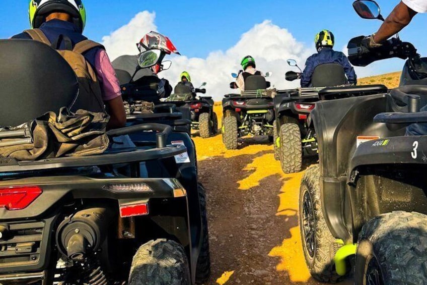 A group of people on ATVs on a dirt road with yellow markings. 1