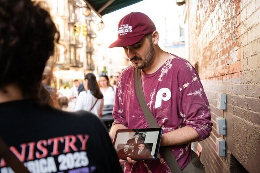 A person wearing a maroon shirt and cap, holding a tablet. 1