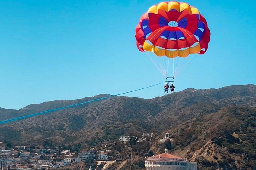 A hot air balloon with a colorful canopy, a cable system, and a mountainous landscape with buildings in the foreground. 2