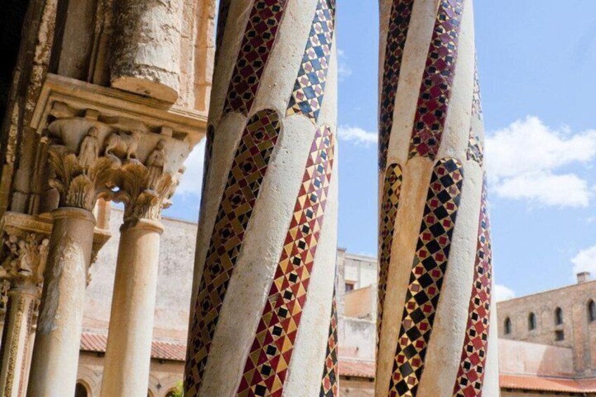 A building with columns featuring geometric tile patterns. 3