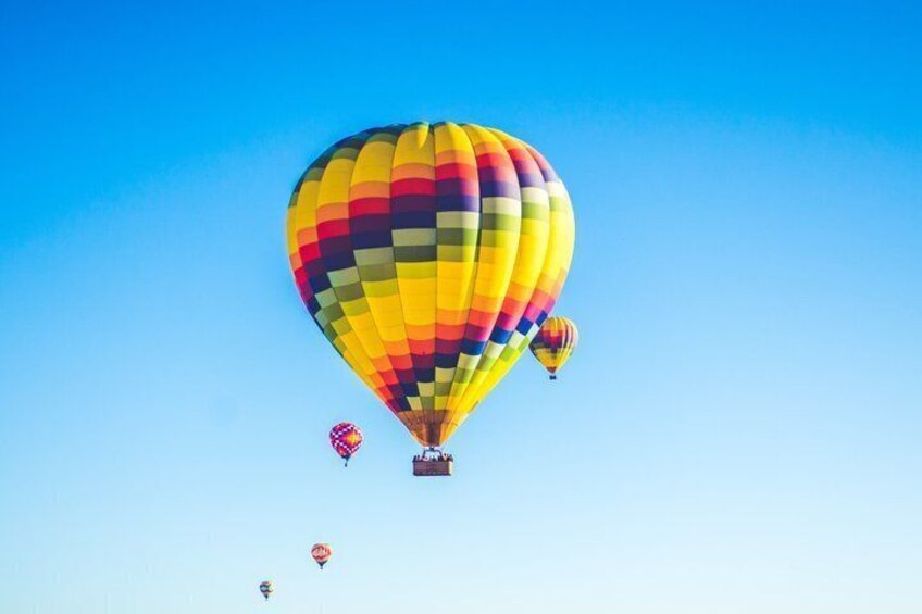 A large hot air balloon with a colorful pattern, flying in a clear blue sky. 1