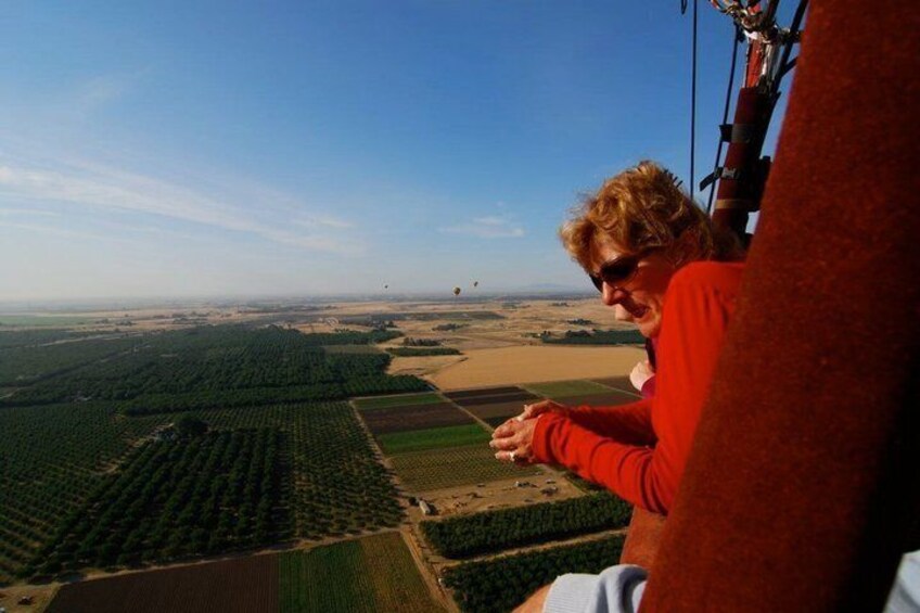 A person in a red shirt looking out over a landscape with fields and a clear sky. 3