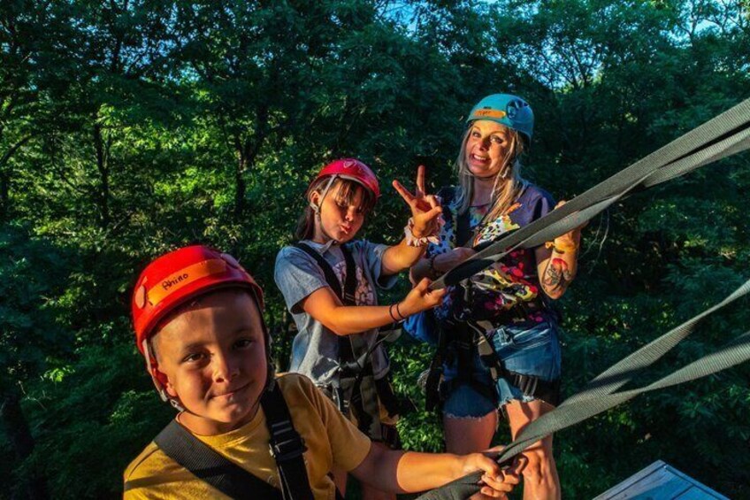 Three people on a zipline with forest in the background. 3