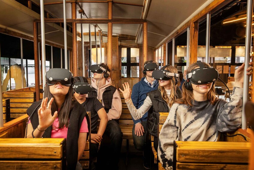 Des personnes portant des casques de réalité virtuelle sont assises sur des bancs en bois à l’intérieur d’un train. 4