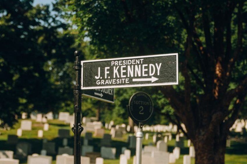 A gravestone with a sign pointing to the President John F. Kennedy gravesite. 5