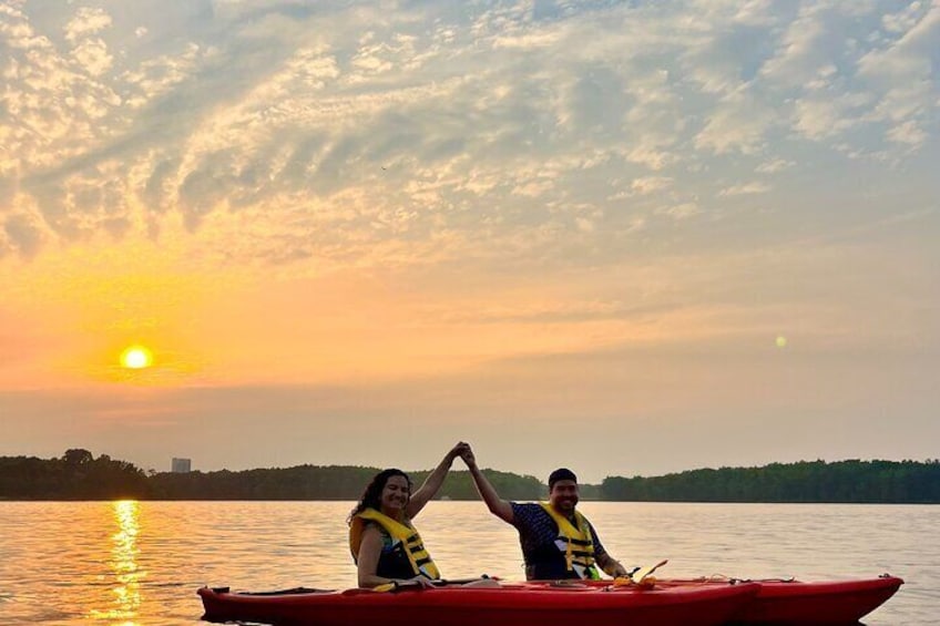 Two people in a red kayak on a calm lake during sunset. 1