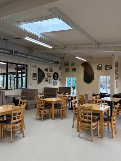 A modern indoor dining area with wooden tables and chairs, large windows, and artwork on the walls. 5