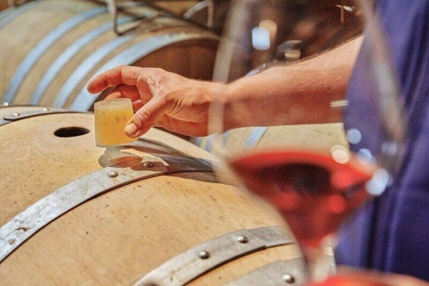 A person pouring liquid from a small container into a wine glass. 2