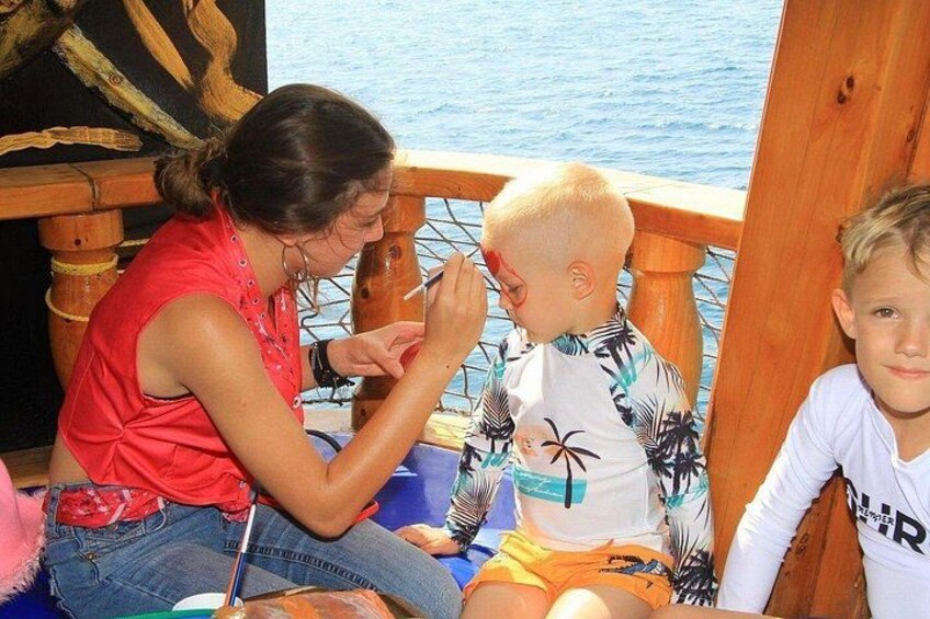 A woman painting a child's face on a boat. 3