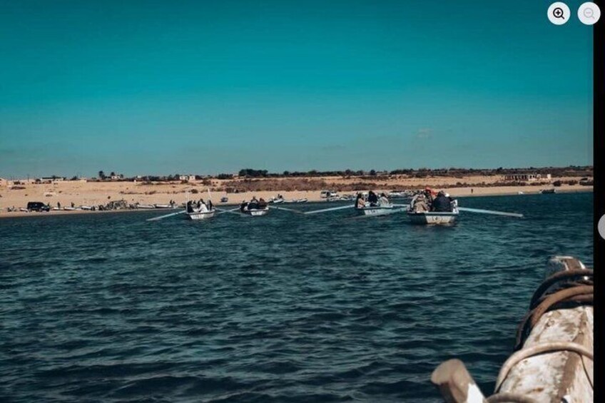 A coastal scene with several small boats on the water, a sandy beach, and a clear sky. 5