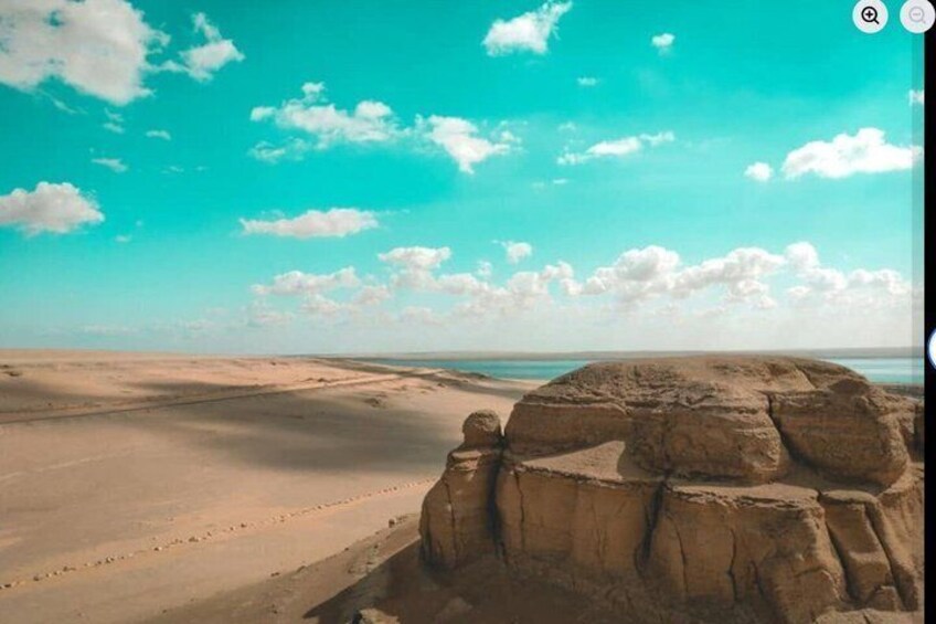 A desert landscape with a prominent rock formation and a clear sky. 4