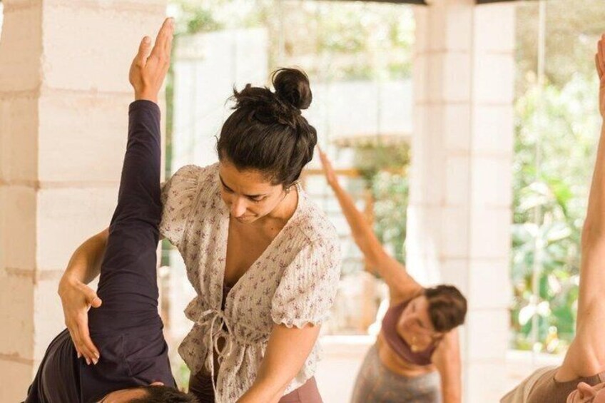 A person performing a stretching exercise indoors with a brick wall and greenery in the background. 5