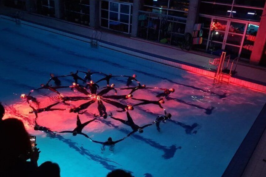 A group of people forming a circle on a pool deck at night. 4