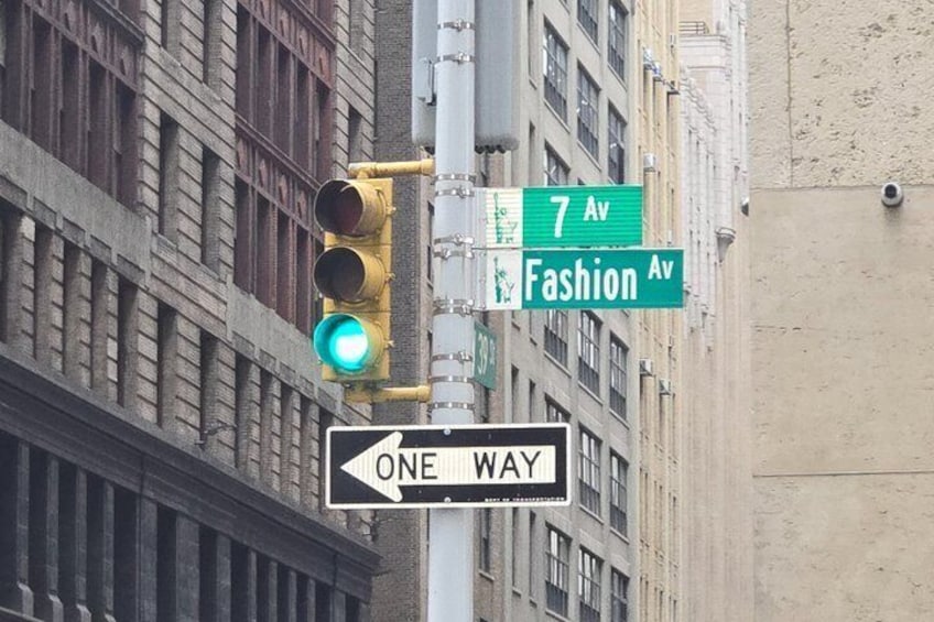 A traffic light, street signs for '7 Av' and 'Fashion Av,' and a 'ONE WAY' sign. 1