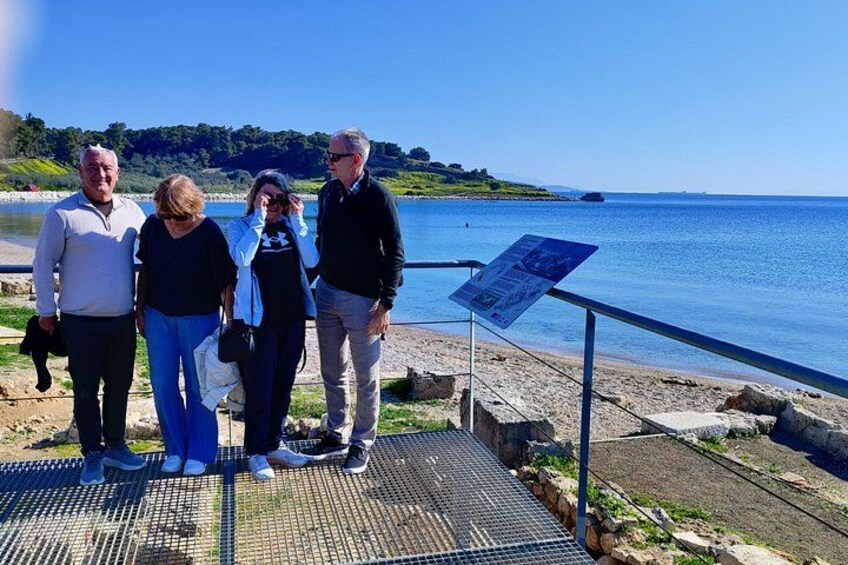 A group of people standing on a metal platform by a body of water with a signboard. 2