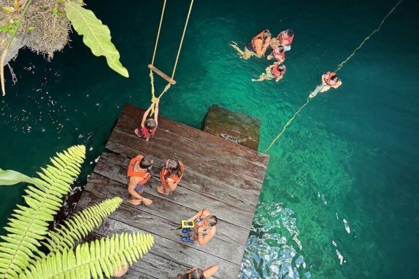 A wooden dock with people swimming in clear water. 1