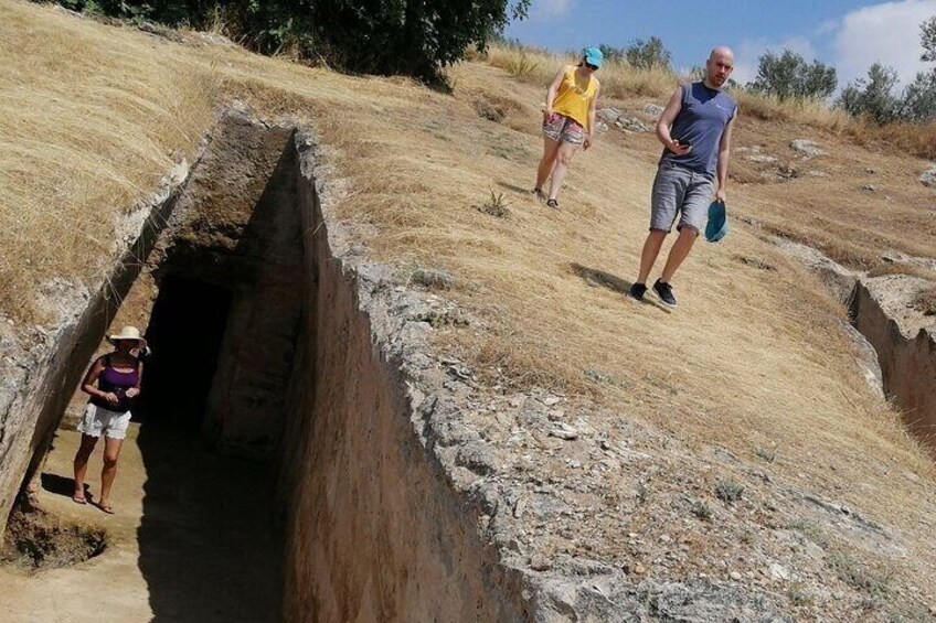 A man walking on a dry, grassy hillside with a trench dug into the ground. 3