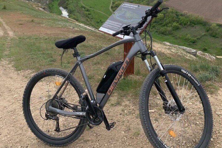 A mountain bike parked on a dirt path with a sign in the background. 4