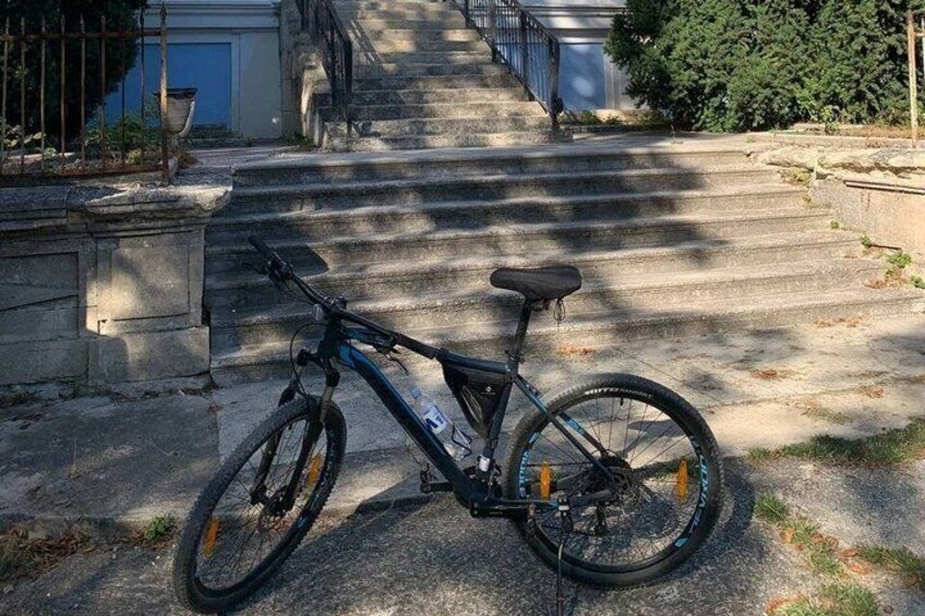 A bicycle parked on a concrete driveway with steps leading to a building. 3