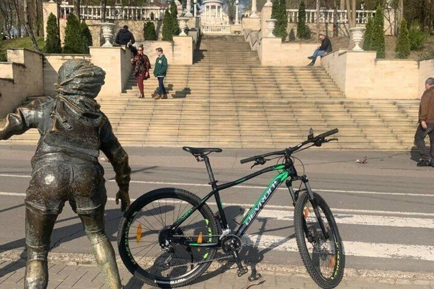 A statue, a bicycle, and a set of stairs in a public square. 5