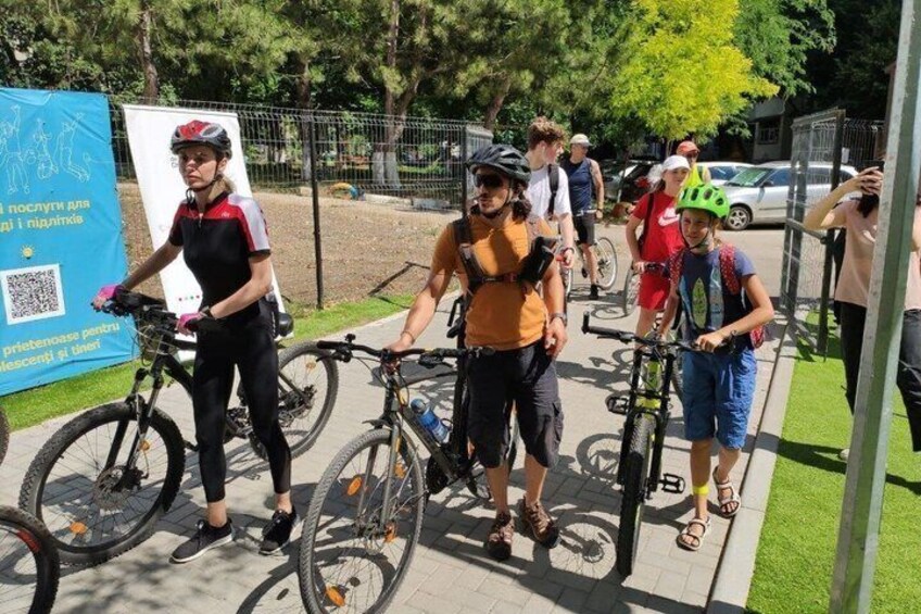 People with bicycles, a blue banner, and a metal fence. 2