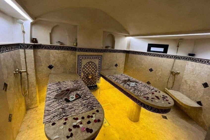 A traditional hammam with two stone basins, tiled walls, and a patterned tile design on the floor. 4