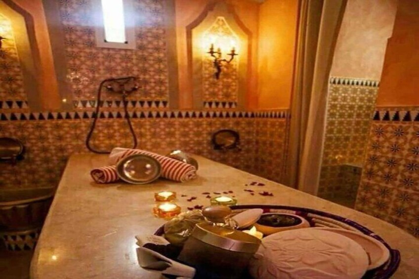 A traditional Moroccan setting with a table set for a meal, featuring a patterned tile wall, a hanging lamp, and a decorative bowl. 3