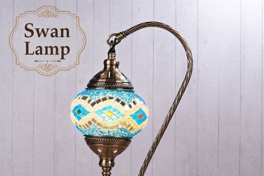 A swan lamp with a decorative blue and white patterned base and a brass stand. 3