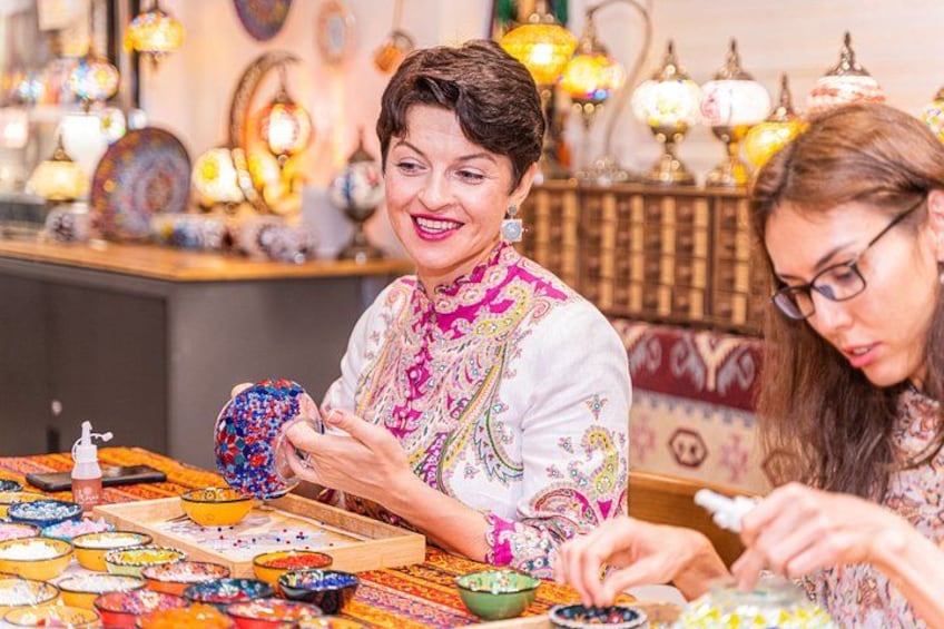 A person arranging colorful bowls on a table with decorative lamps in the background. 4