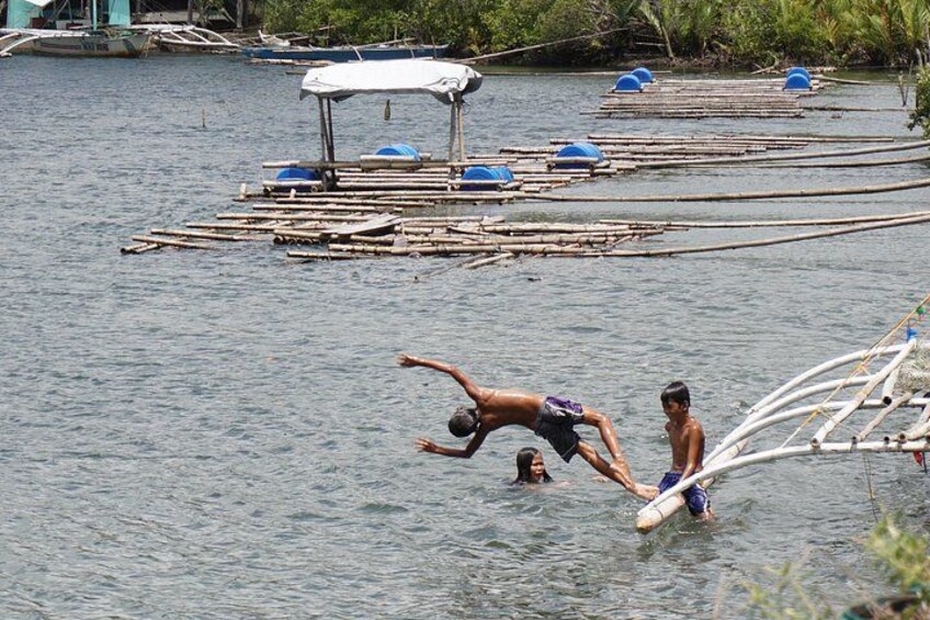 A man diving into water from a dock, surrounded by floating structures and boats. 2