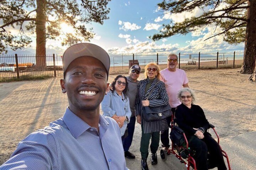 A group of people at a beach with a fence and trees in the background. 5