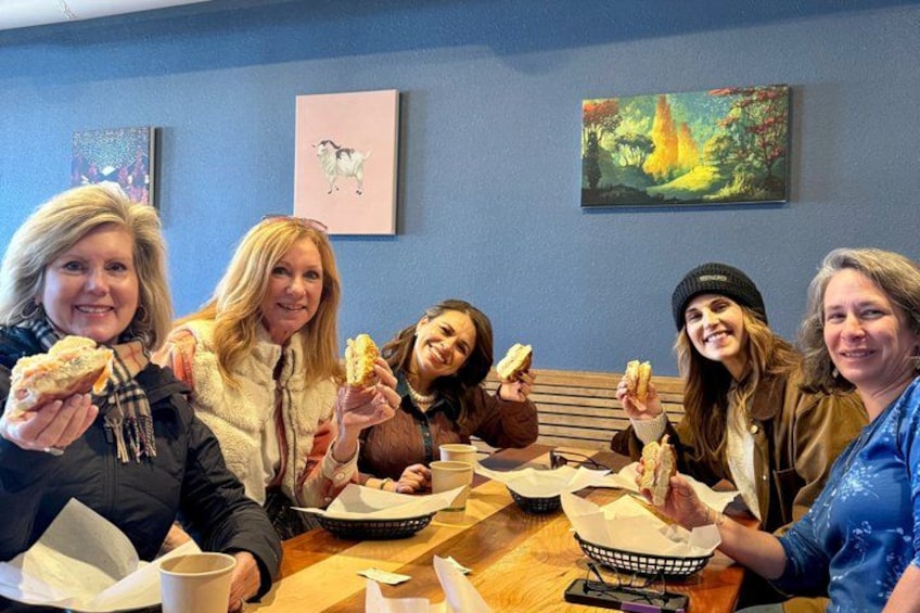 A group of people sitting at a table, eating sandwiches. 2