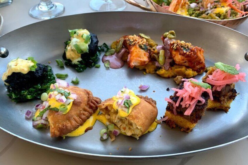A variety of appetizers on a metal tray, including items with cheese, greens, and pink toppings. 3