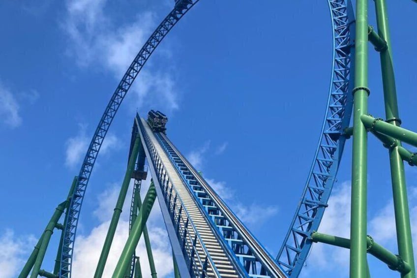 A roller coaster with a steep drop and green supports against a clear blue sky. 4