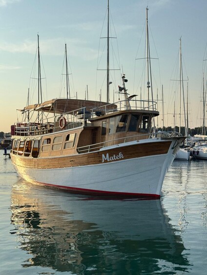A wooden boat named 'Matek' docked at a marina with other boats in the background. 1