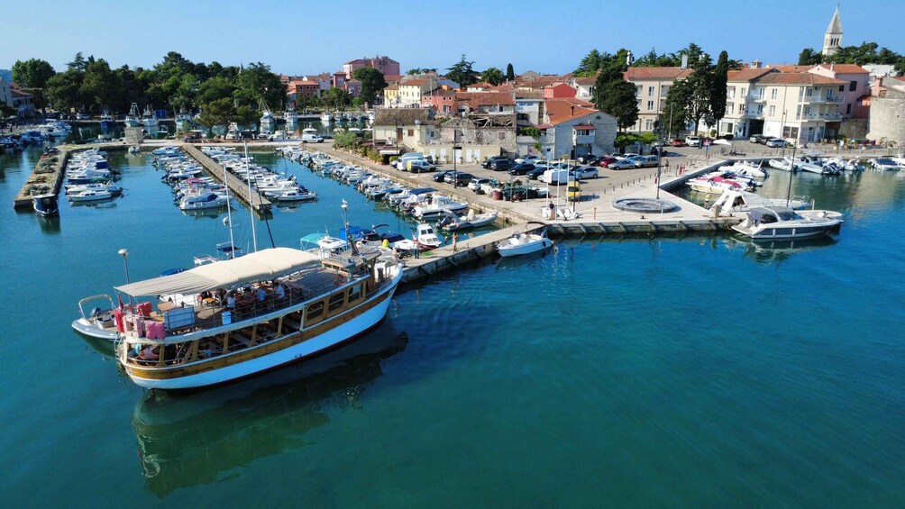 A marina with boats docked, a large boat with passengers, and buildings in the background. 5