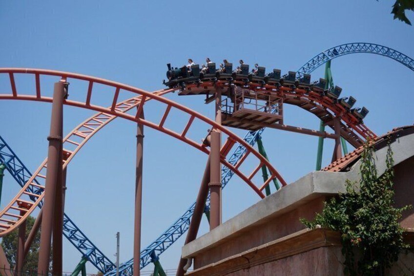 A roller coaster with a red track and a blue support structure. 2