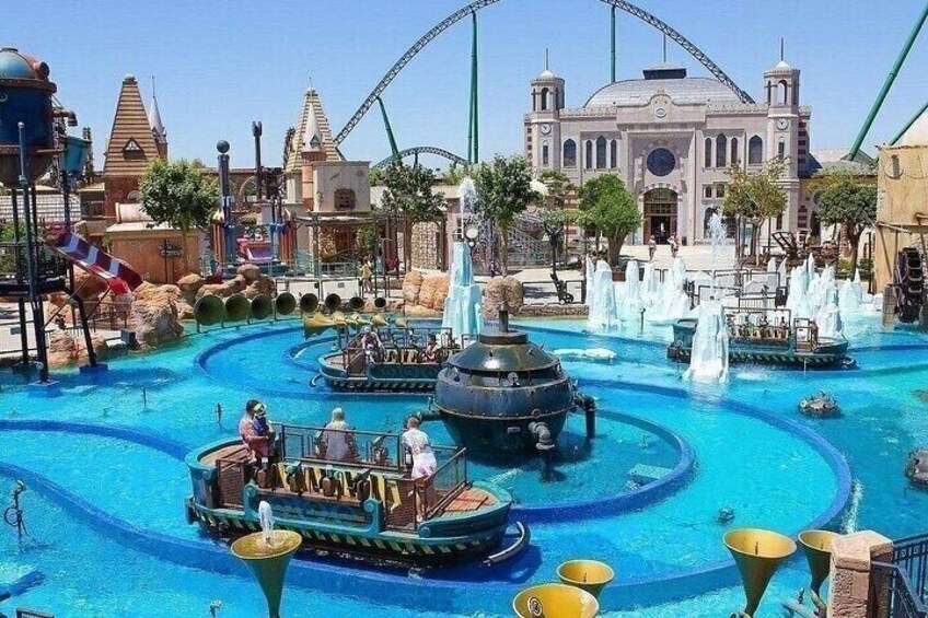 A water park with a large fountain, boats, and a roller coaster in the background. 4