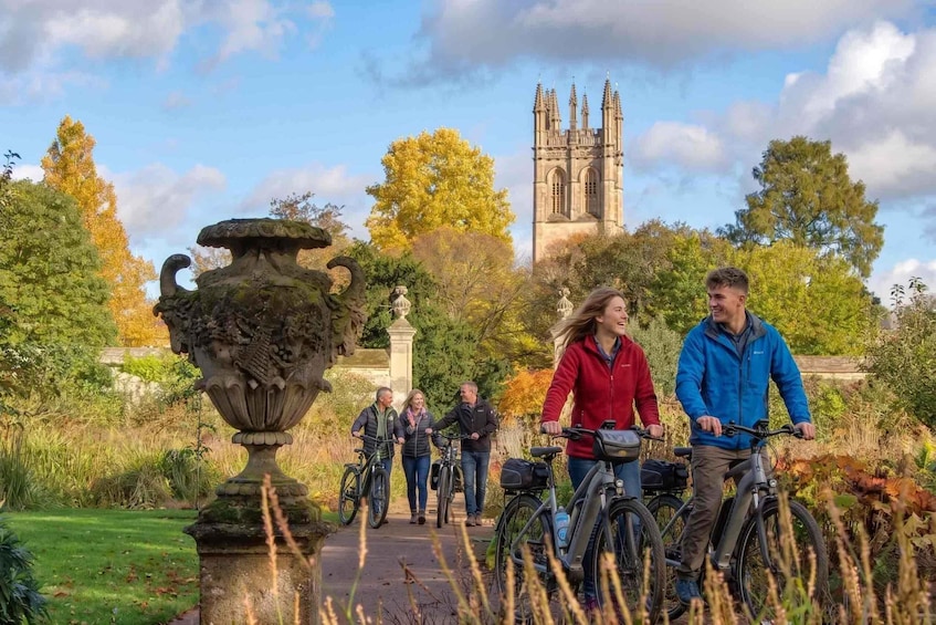 A group of people cycling and walking in a park with a historic building in the background. 4
